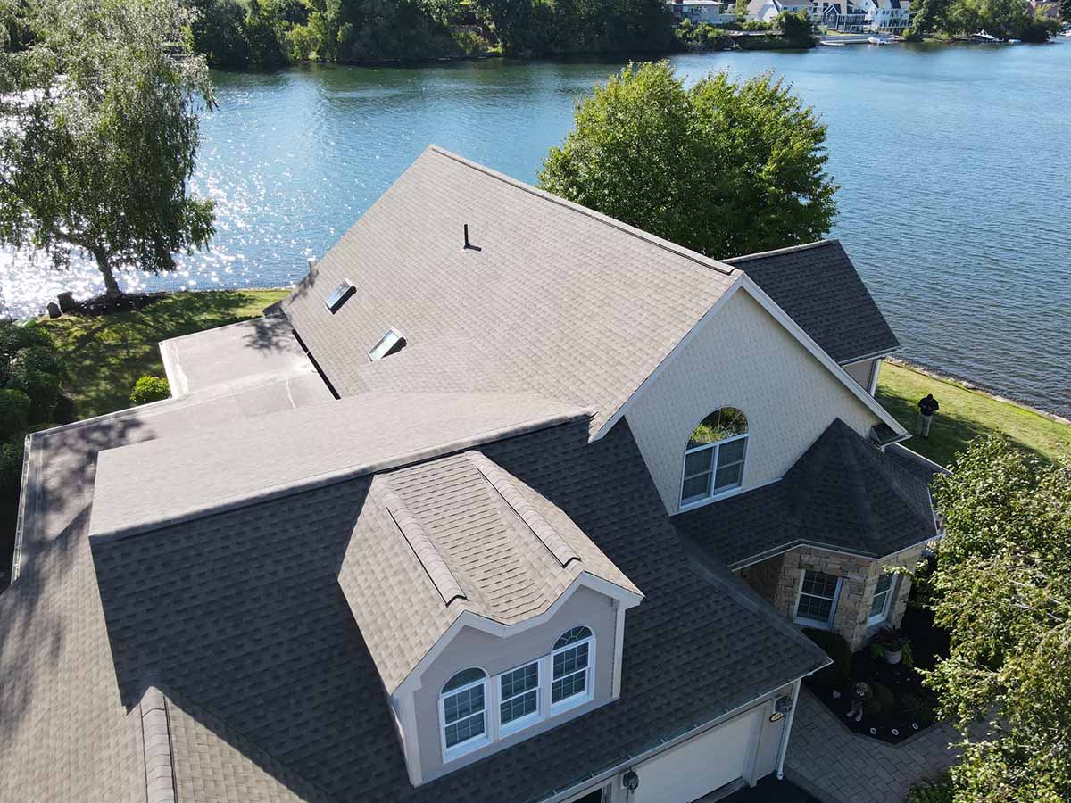 An aerial view of CertainTeed Roofing Shingles on a house with a body of water in the background. CertainTeed Roofing Shingles - CertainTeed vs. Atlas Shingles - January 2023 Blog Post (3)