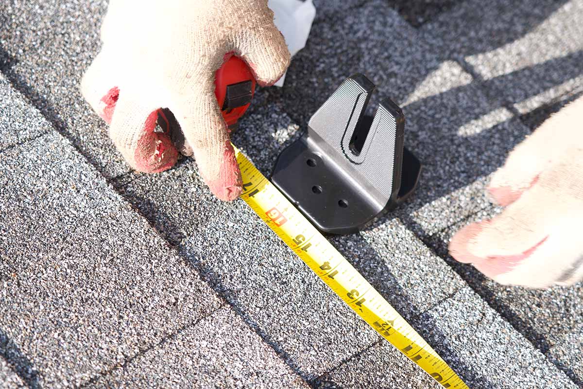 Close up view of a contractor measuring for solar panel installation. Going Solar in MA - A step by step guide.