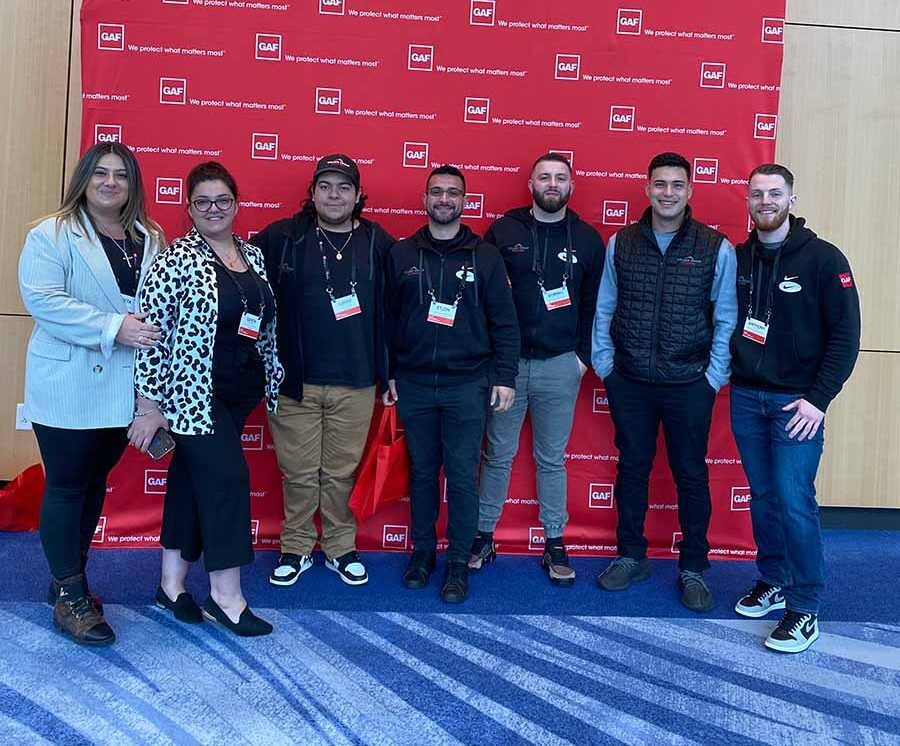 Golden Group team with GAF sign in background.How To Find a Roof Warranty that Guarantees Protection.