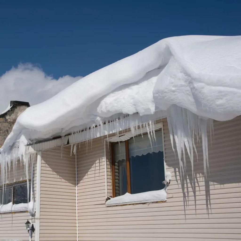 Large icicles and snow on a residential roof in Massachusetts. ice melt for roofs concept.
