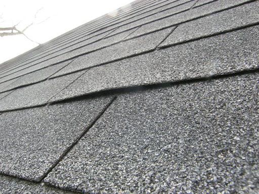 Close view of lifted shingled installed on a roof.