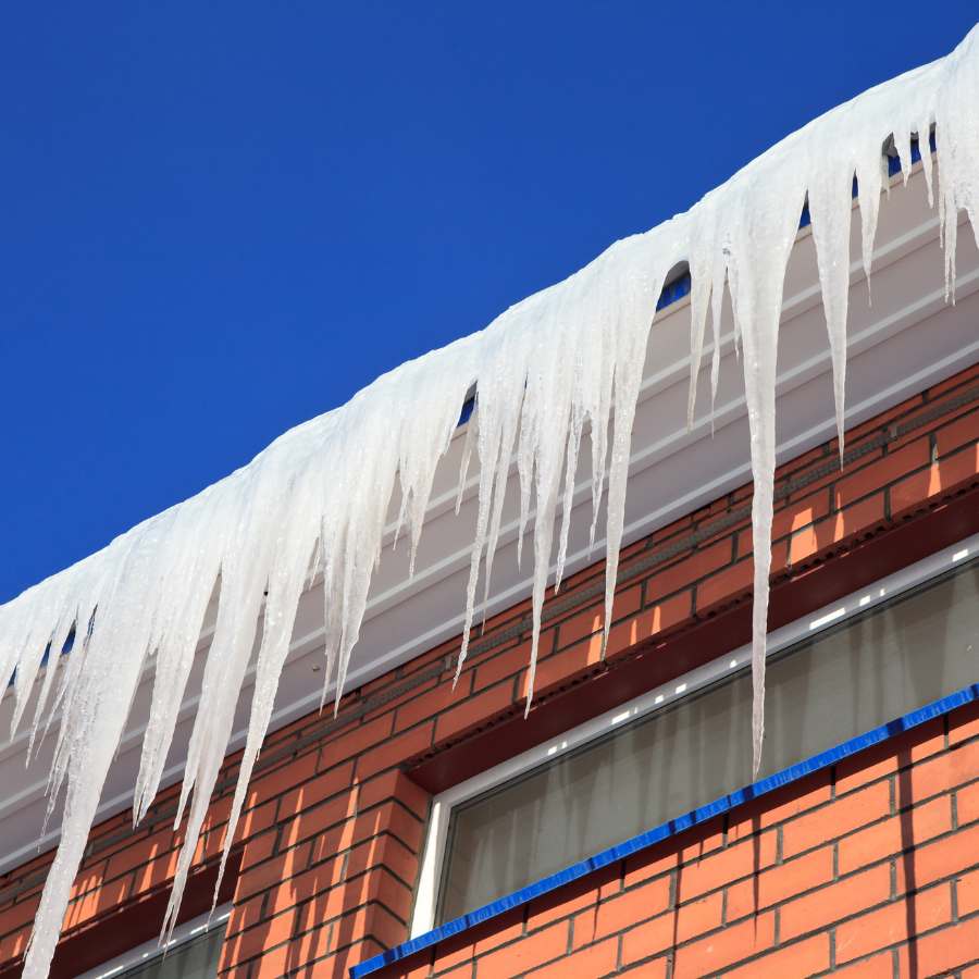 Large icicles and snow on a residential roof in Massachusetts. ice melt for roofs concept.