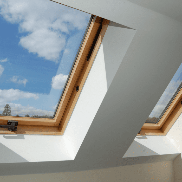 View of a roof skylight from inside the home with wooden capping on a white ceiling.