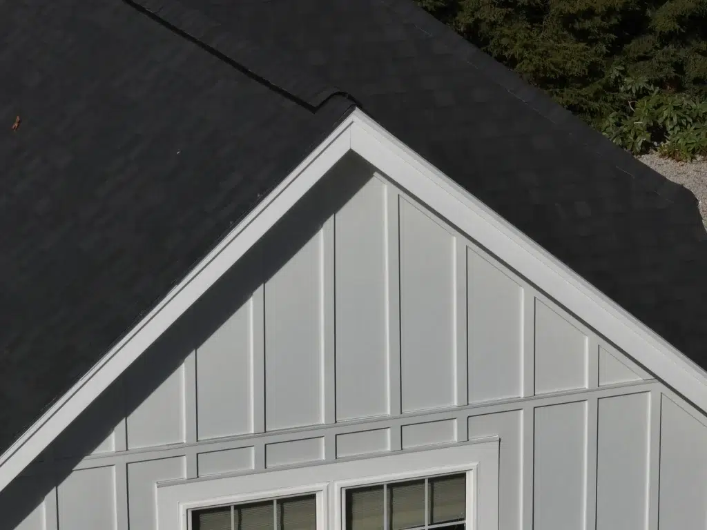 Aerial view of a professional siding job completed on a gable roof with white siding in Hudson, MA