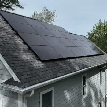 Side angle view of a residential home by a lake with solar panels on a slanted roof by the Golden Group