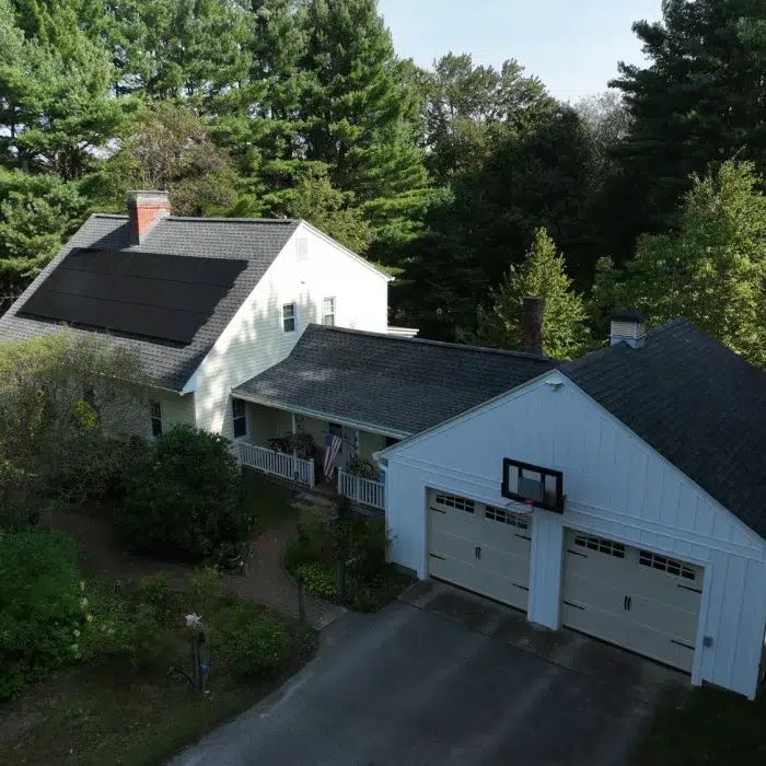 Aerial view of a Solar Energy Solution in Sudbury, MA on a residential home with a two car garage and driveway