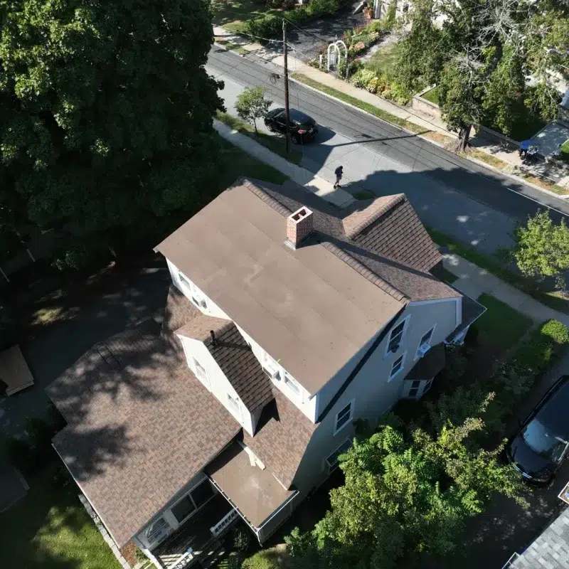 Aerial view of a half completed Roof Construction Project in Hopkinton, MA with second half of roofing being prepared for new shingles.
