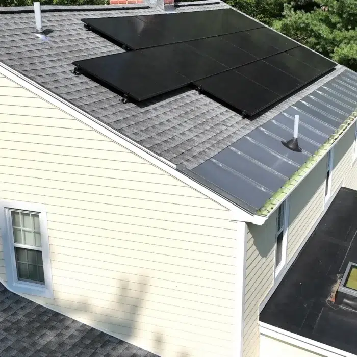Solar panels on a slanted grey shingled residential roof with vinyl siding in Framingham, MA
