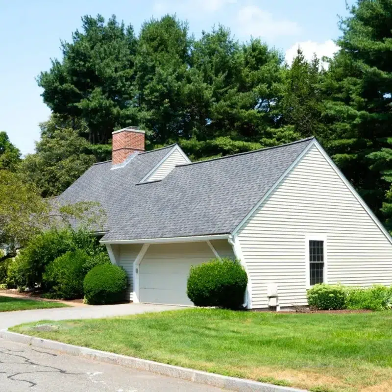 New siding and roof top on a residential home in Wayland, Massachusetts surrounded by trees and landscaping.