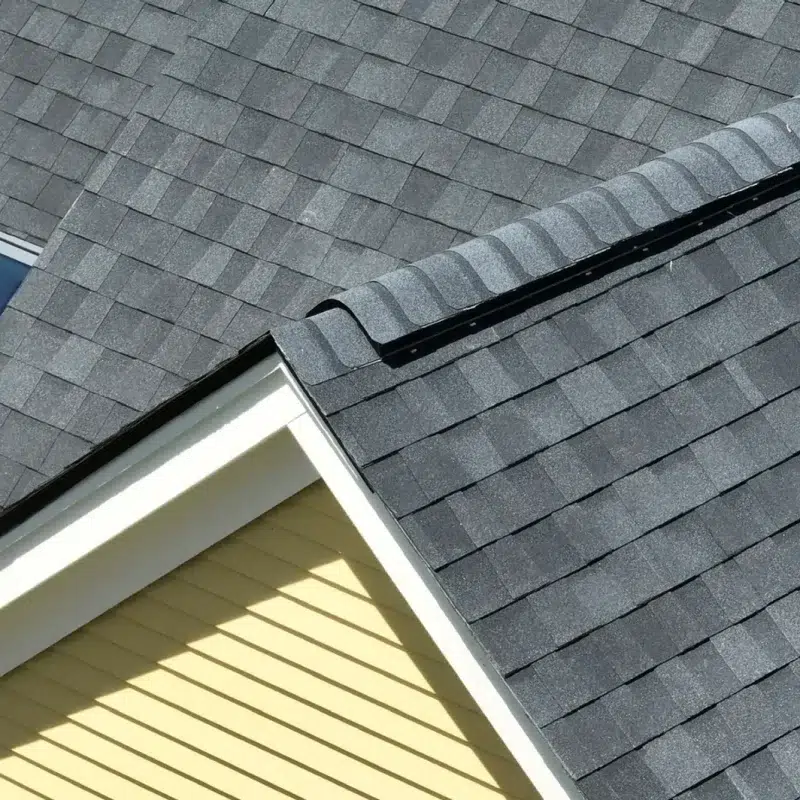 Close view of a Full Roof shingled Installation in Sudbury, MA with a skylight and yellow home siding.