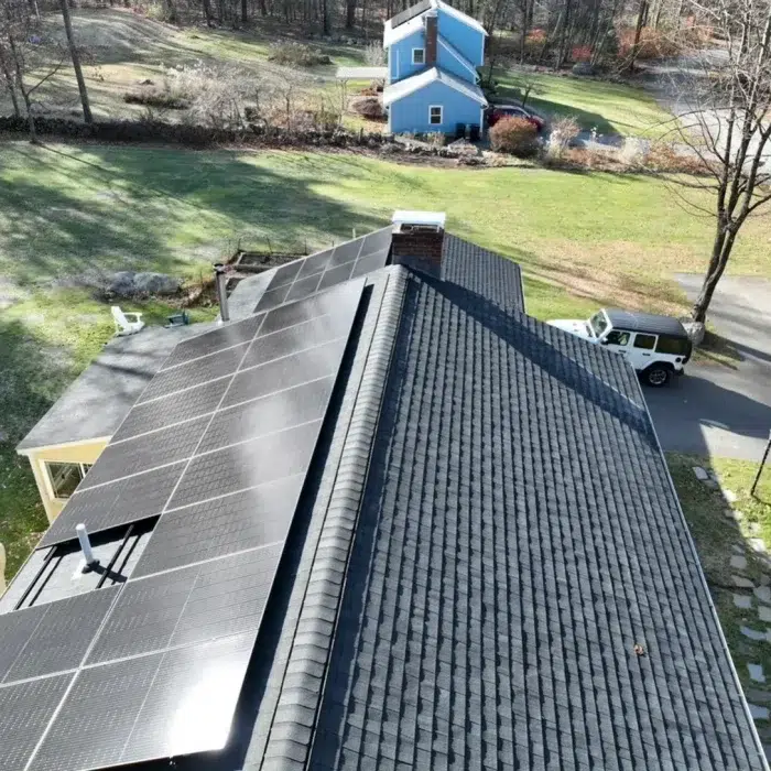 Solar panels on a slanted shingled residential roof surrounded by grass in Westborough, MA