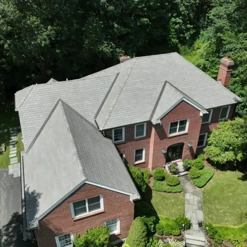 Aerial view of a large residential home with new shingled roof in Concord, Massachusetts